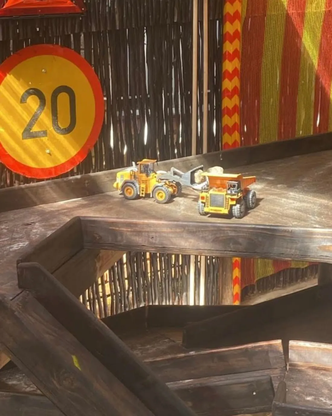 Front loader and dump truck on the upper level beside a 20 speed sign